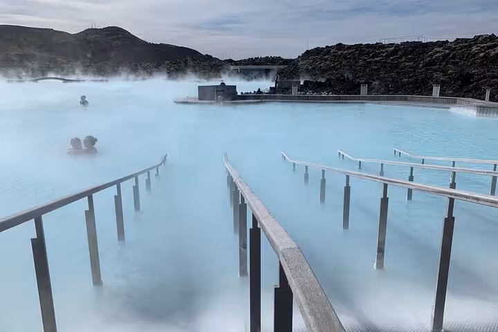 Steaming milky blue geothermal waters of the Blue Lagoon spa in Iceland with bathers and misty landscape