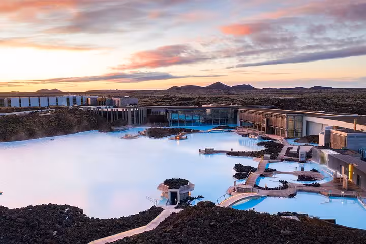 Aerial view of Blue Lagoon geothermal spa with milky blue waters and modern facilities at sunset, Iceland