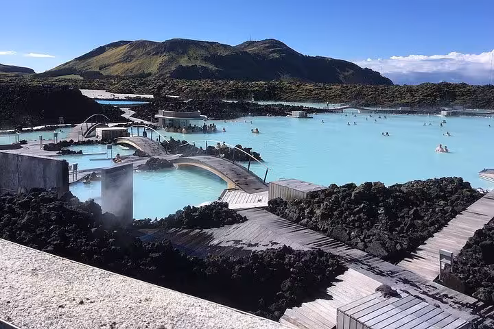 Blue Lagoon geothermal spa with milky blue waters surrounded by black lava rocks and mountains in Iceland