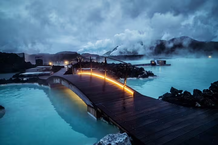 Blue Lagoon geothermal spa with glowing wooden bridge over milky blue waters in Iceland at dusk