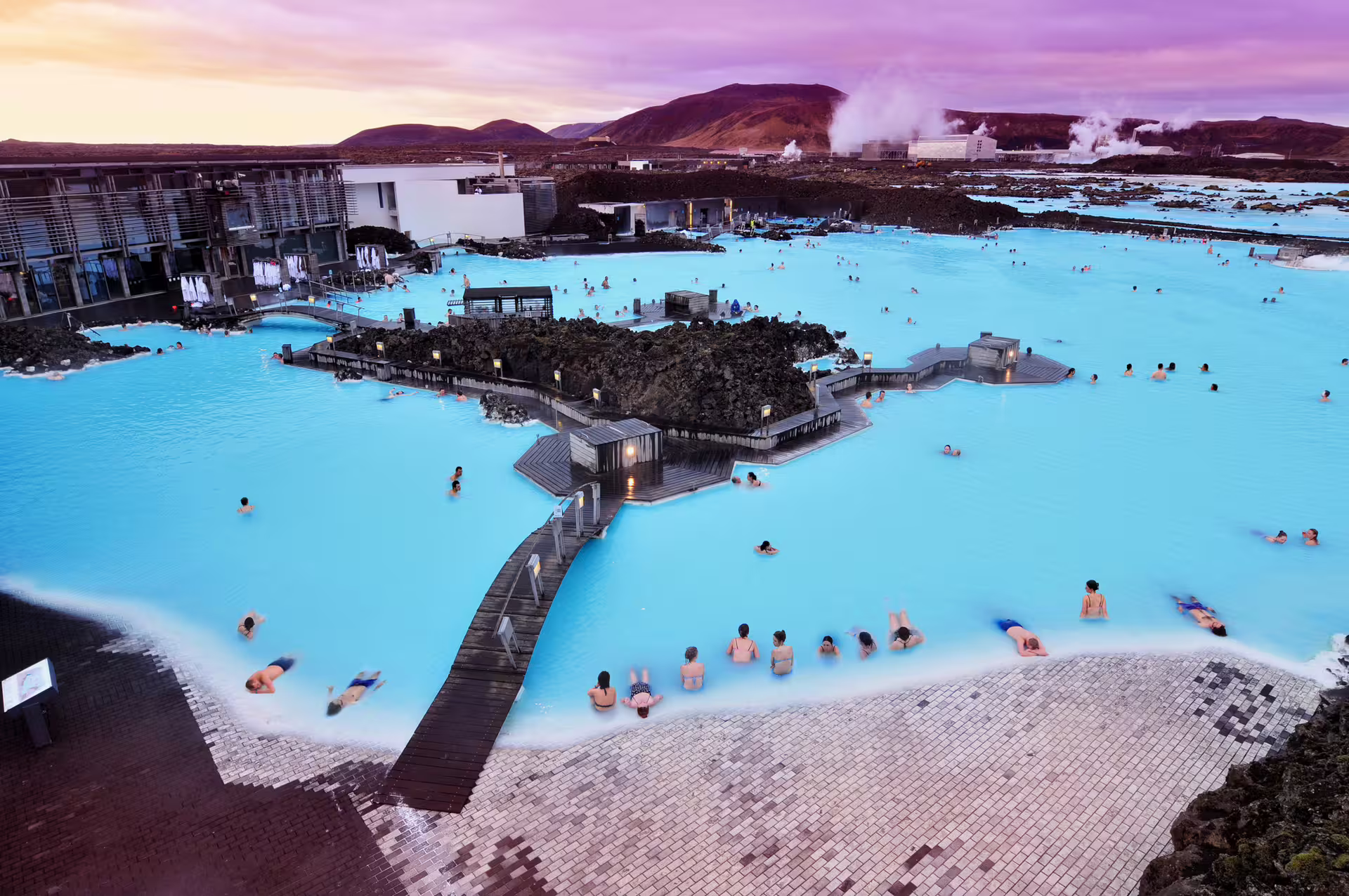 Aerial view of Blue Lagoon geothermal spa with milky blue waters and bathers at sunset, Iceland
