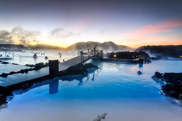 Blue Lagoon geothermal spa glowing blue waters with steam rising at sunset in Iceland
