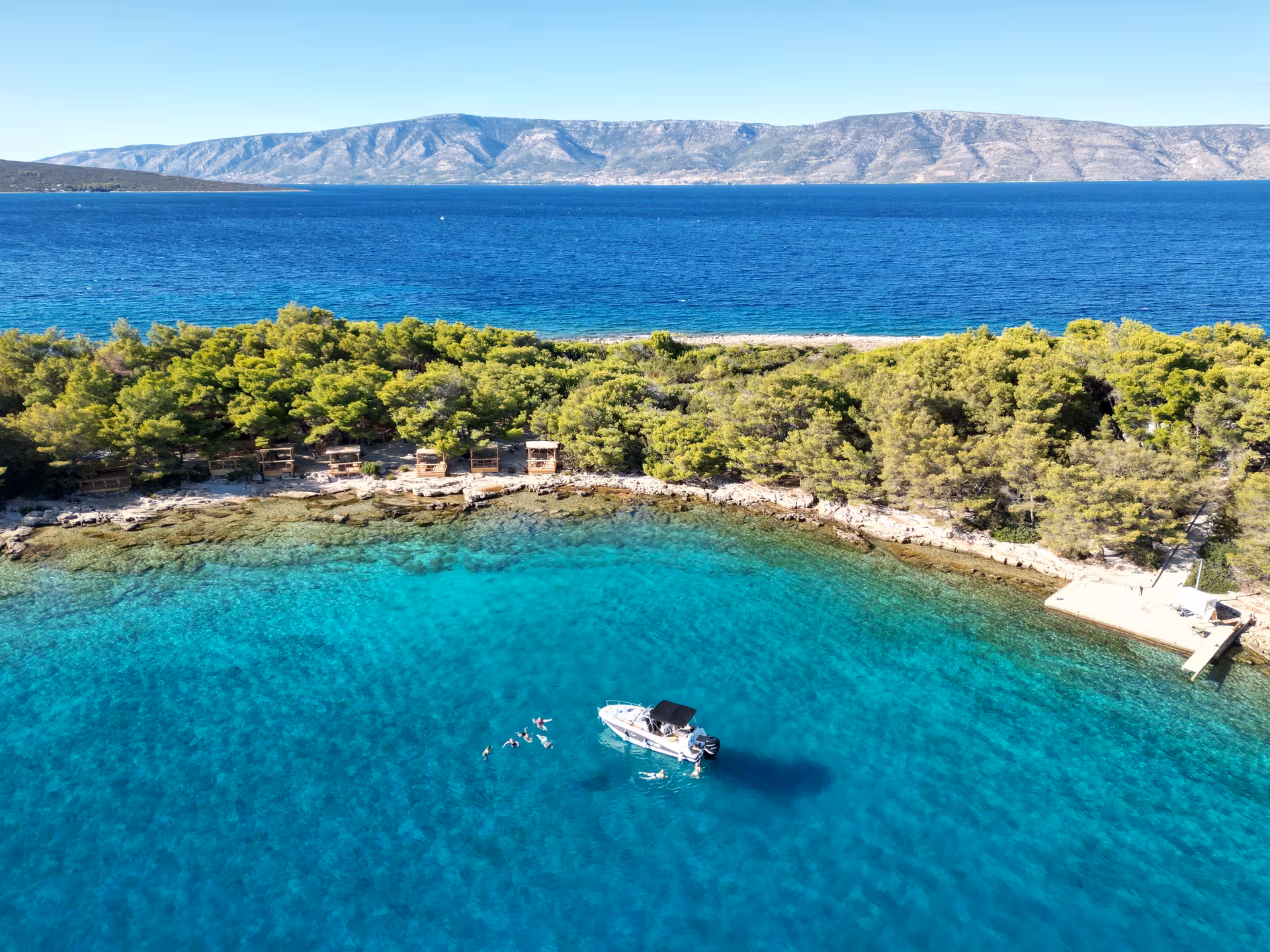 Boat and swimmers in turquoise Blue Lagoon cove on 3 Islands tour to Golden Horn Beach and Jelsa Town, Hvar