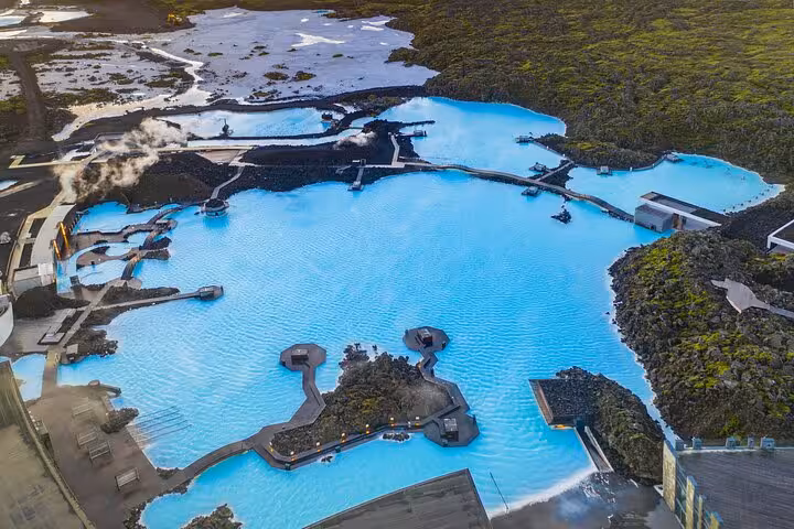 Aerial view of Blue Lagoon geothermal spa with vivid turquoise waters surrounded by black lava fields, Iceland