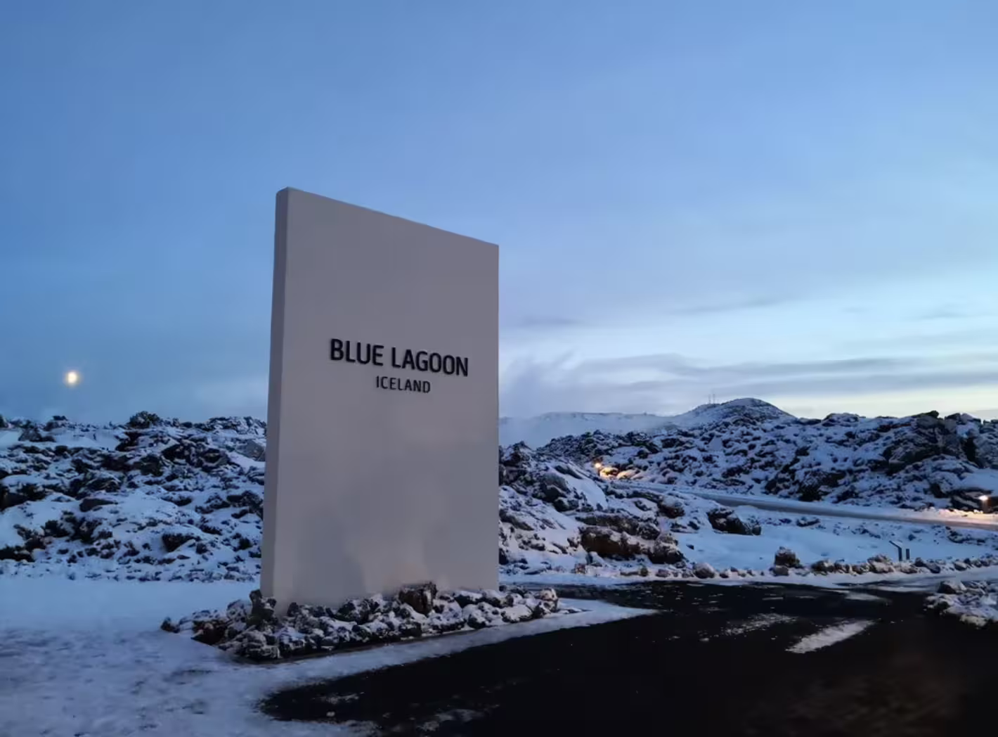 Blue Lagoon Iceland entrance sign surrounded by snow-covered lava fields at dusk