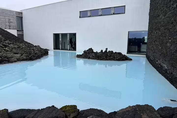 Milky blue geothermal waters of Blue Lagoon Iceland surrounded by dark lava rocks and white building