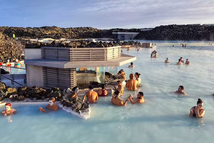 Tourists bathing in the milky blue geothermal waters of Blue Lagoon Iceland with lava rocks