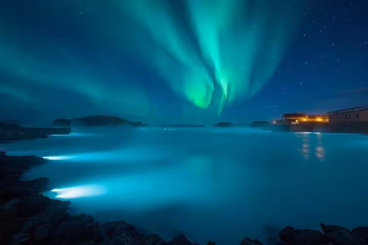 Northern lights dancing over the glowing blue geothermal waters of Blue Lagoon, Iceland at night