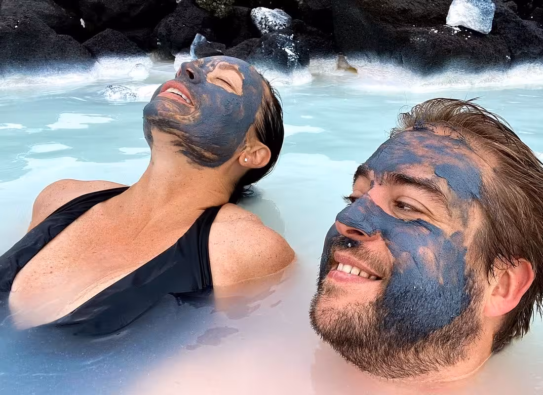 Couple enjoying silica mud masks in the milky blue geothermal waters of Blue Lagoon Iceland