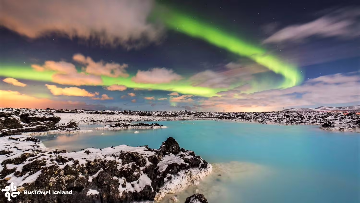 Northern lights aurora borealis over Blue Lagoon geothermal pool with snow-covered lava rocks in Iceland