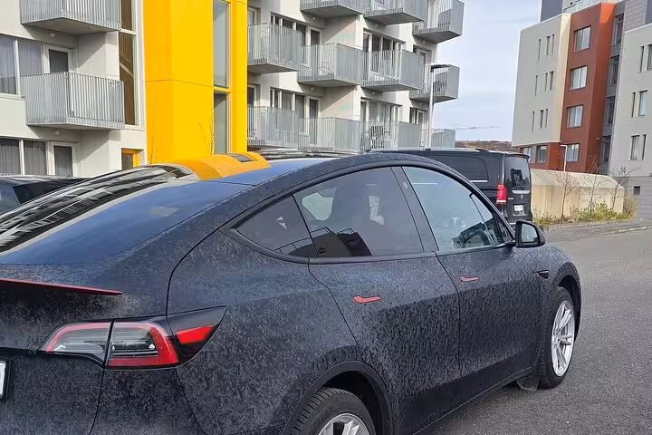 Sleek black car parked near modern apartments, ideal for private transfers between Reykjavik and Keflavik.