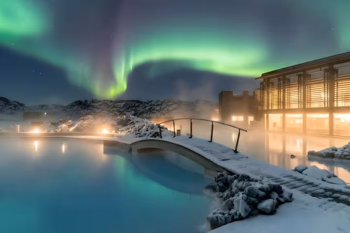 Blue Lagoon geothermal pool with aurora borealis over snowy Iceland landscape at night