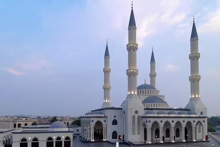 Beautifully lit Blue Mosque in Dubai at dusk, showcasing its architectural grandeur in a private day tour.