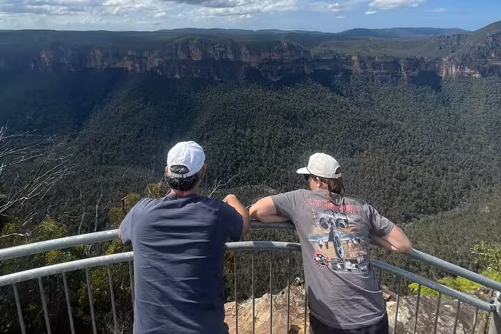 Two men overlooking the expansive Blue Mountains vista from a lookout point during a private group tour.