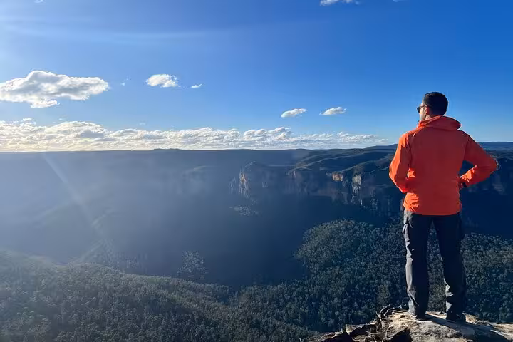 Person in red jacket enjoying panoramic view of Blue Mountains on private daily group tour under clear blue sky.