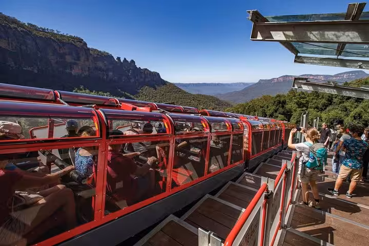 Tourists boarding red scenic railway with stunning Blue Mountains backdrop on private daily group tour adventure.
