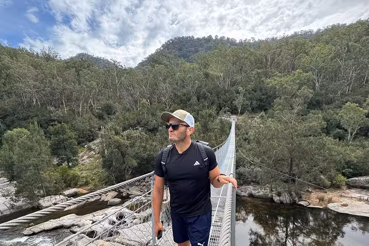 Hiker crossing a suspension bridge surrounded by lush forest in Blue Mountains, ideal for adventurous private tours.