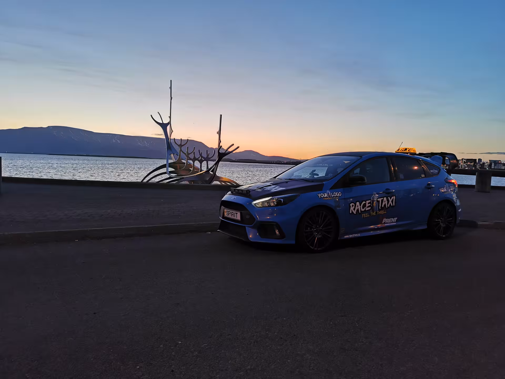 Blue race taxi by Reykjavik waterfront at sunset, Golden Circle Rally Car Experience pickup and drive