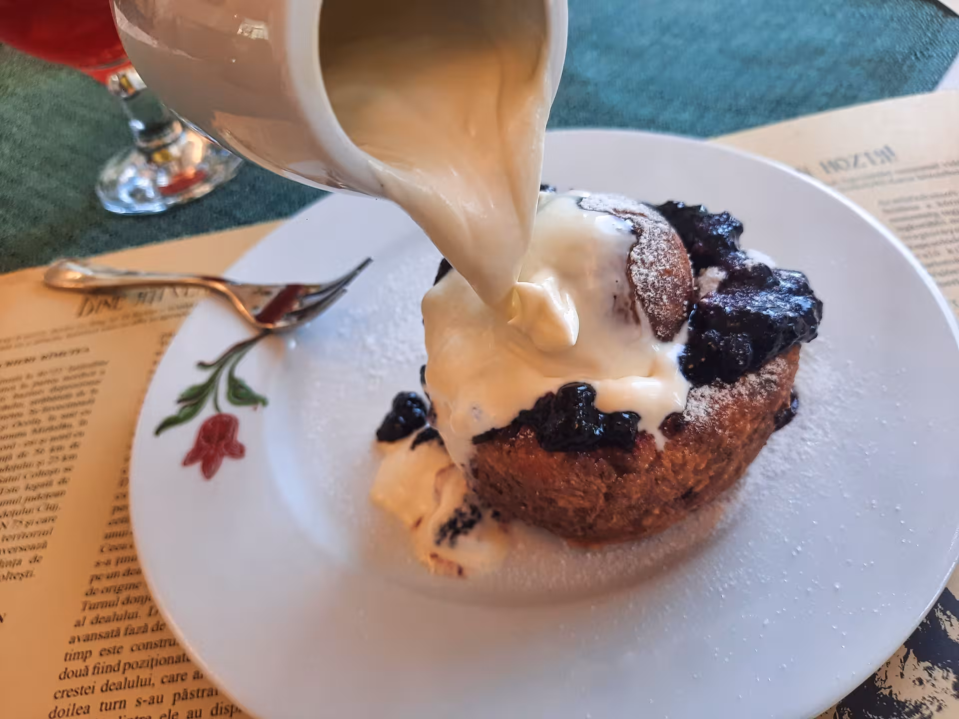 Creamy sauce poured over a blueberry dessert during a guided dinner tour in Rimetea Apuseni Mountains Romania
