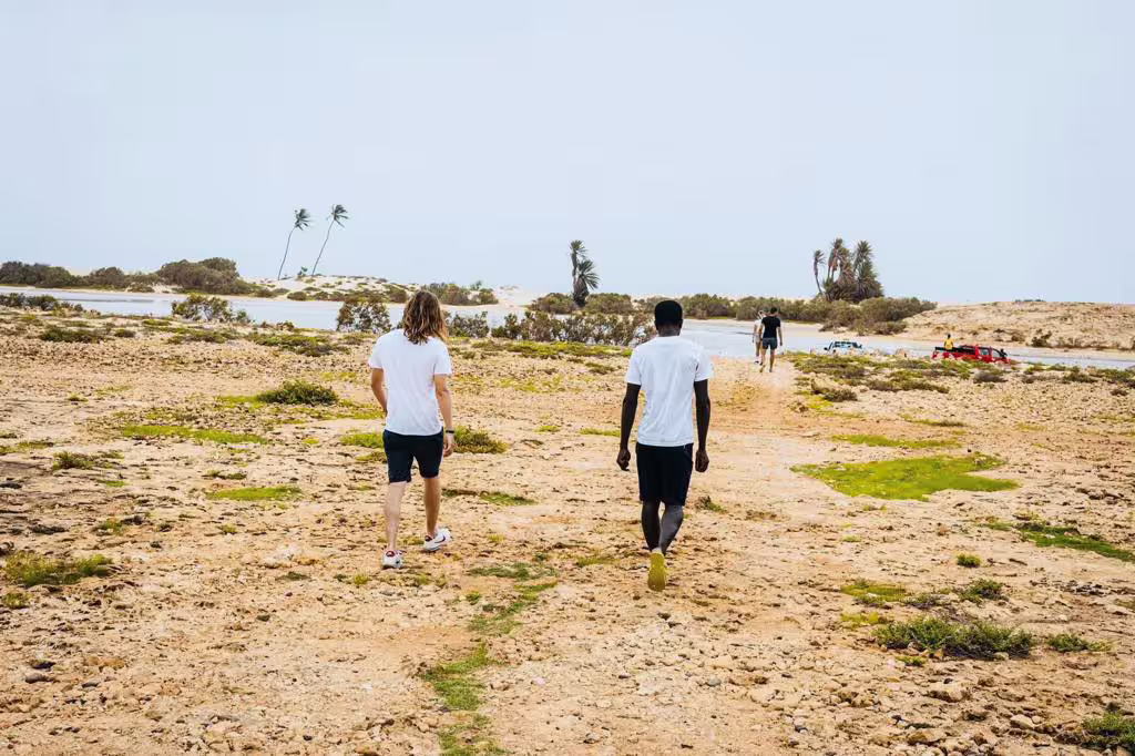 Guests walking across Boa Vista coastal flats toward a lagoon on the wild beaches and Viana Desert day trip