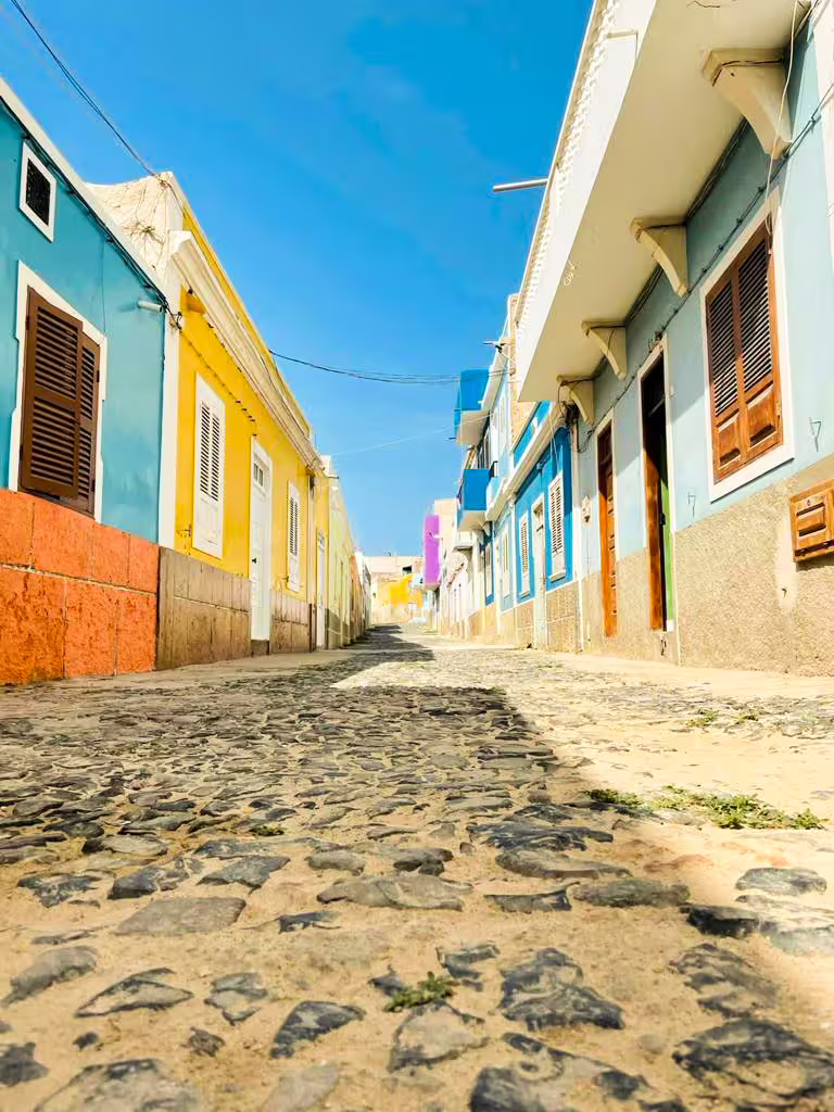 Colorful cobblestone street lined with vibrant houses on Boa Vista island tour.
