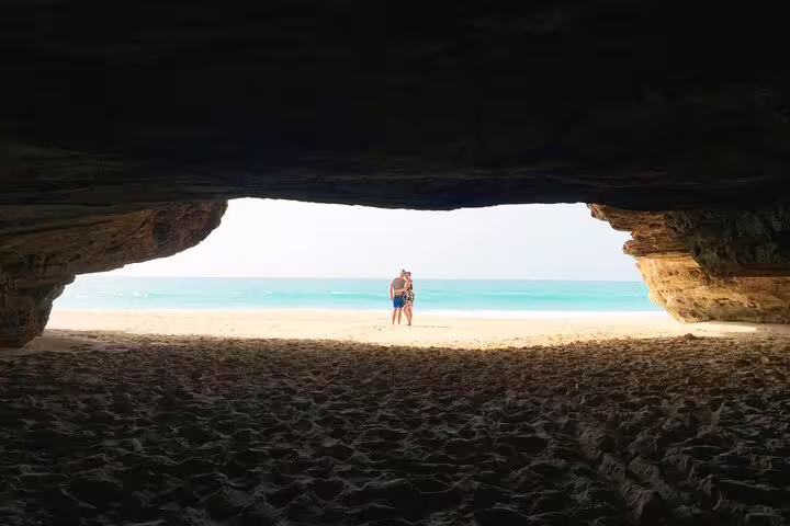 Couple enjoying a scenic view from inside a cave overlooking Boa Vista Island's pristine beach.