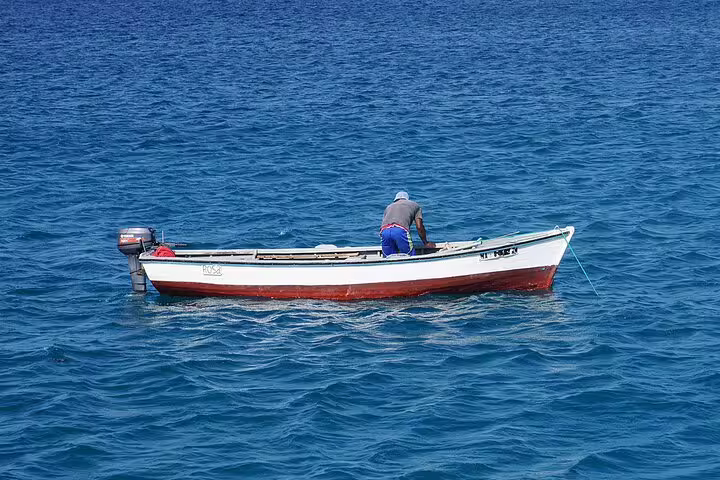 Fisherman on a small boat navigating the clear blue waters off Boa Vista Island, showcasing local maritime culture.