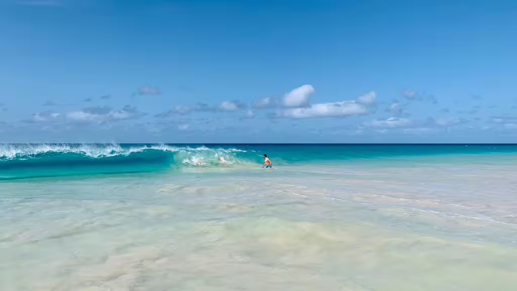 Lone swimmer near rolling Atlantic wave on Boa Vista Island, showcasing wild beaches on the Viana Desert full-day excursion