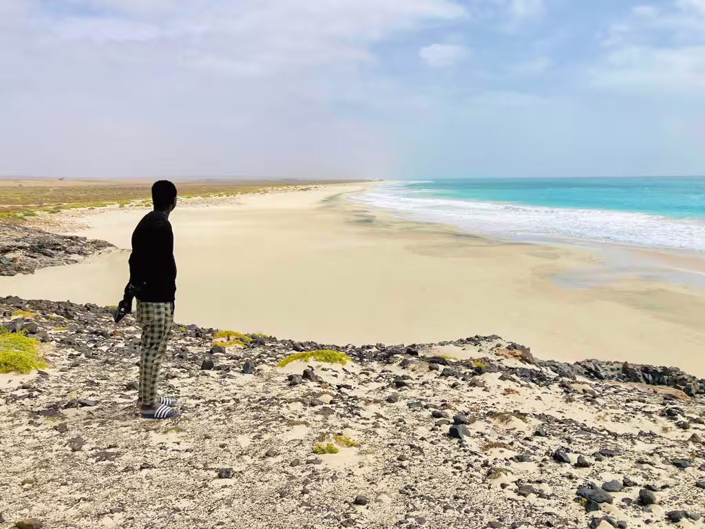 Traveler overlooks Boa Vista wild beach on full-day tour, turquoise Atlantic waves and volcanic rocks