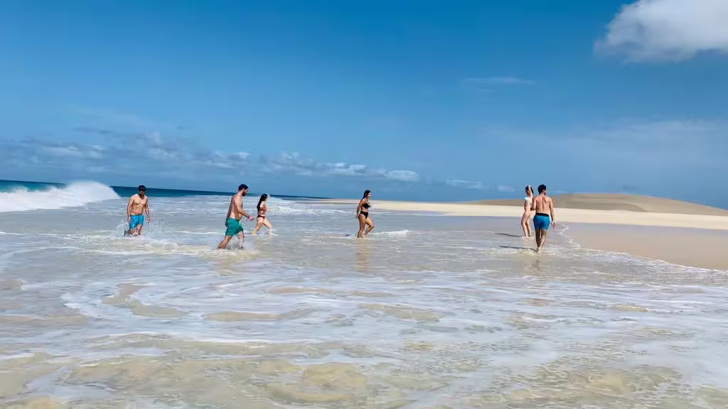 Group wading along turquoise shoreline and sand dunes on Boa Vista, a stop on the Wild Beaches & Viana Desert day trip