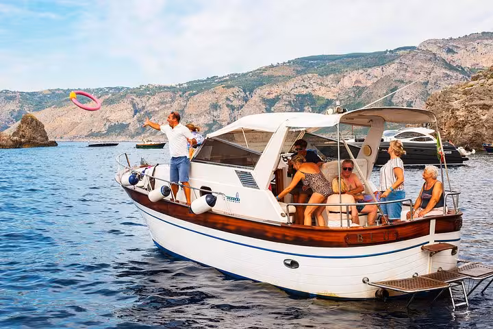 Tourists having fun on a boat near Capri Island, enjoying the picturesque coastline during a Sorrento day trip.