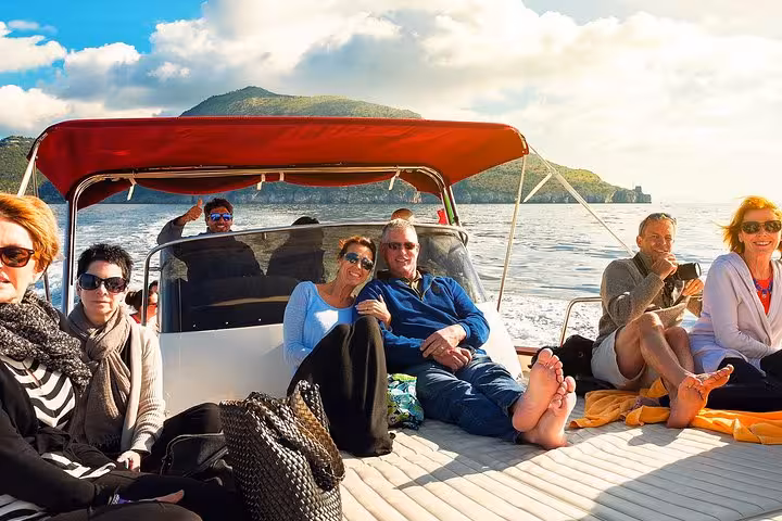 Group of tourists enjoying a sunny boat excursion from Sorrento to Capri Island, surrounded by scenic views.