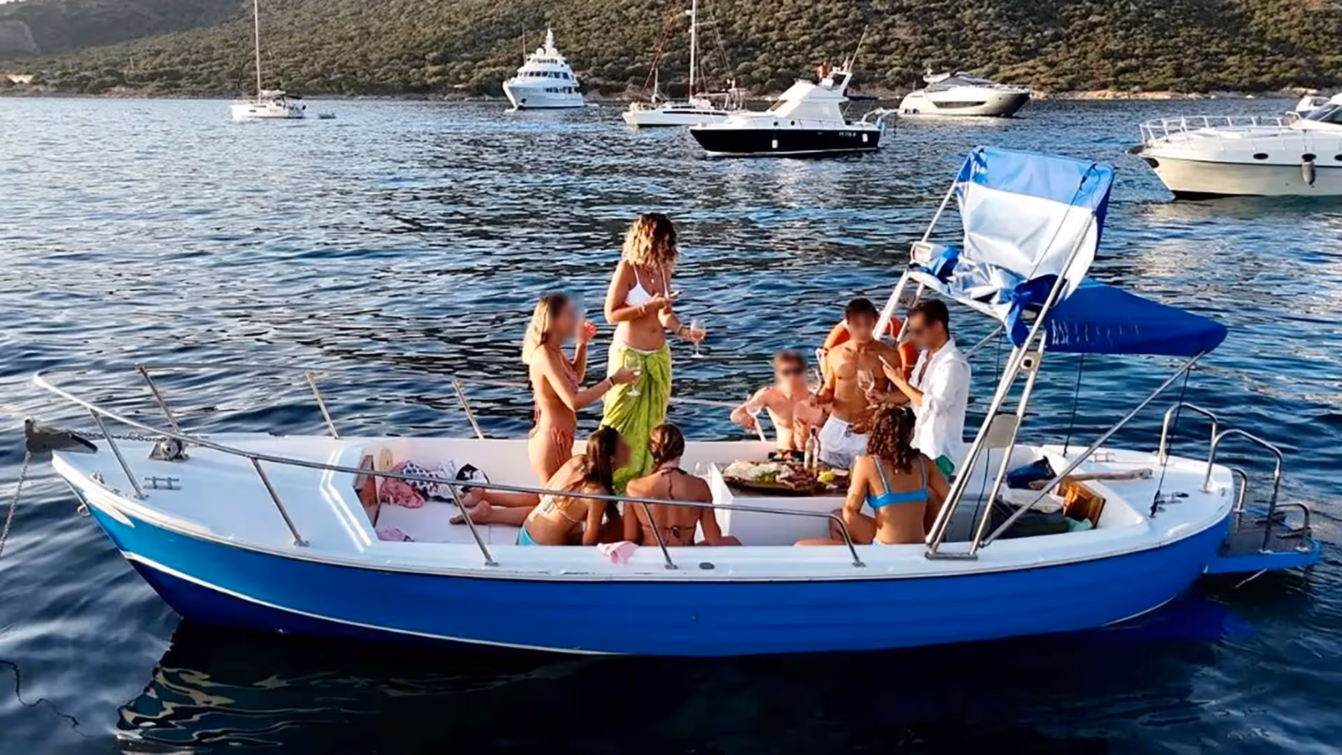 Group enjoying a lively boat party near Porto Cervo, surrounded by yachts in the scenic waters of Sardinia.