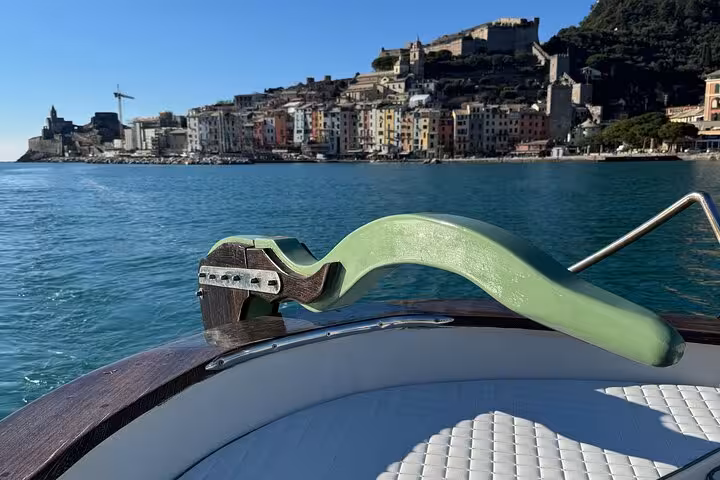 Close-up of a boat's railing with the vibrant coastal town of Cinque Terre in the background.