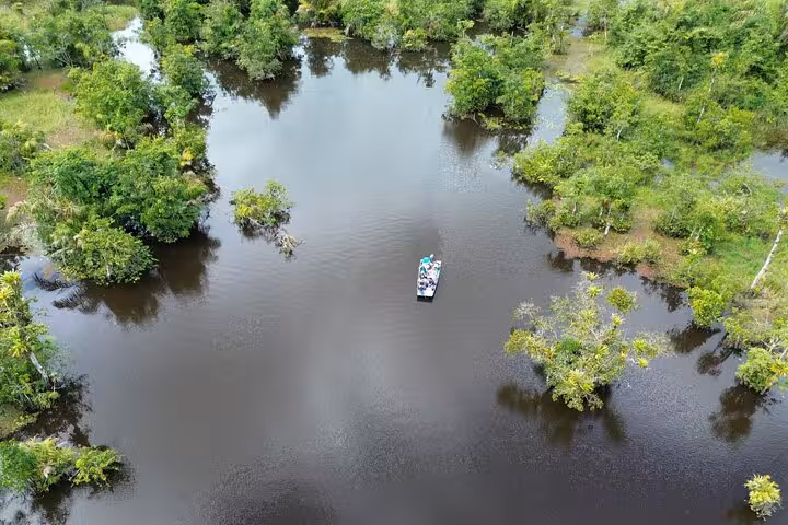 Aerial view of a boat navigating through the serene waters of Rio Frio surrounded by lush tropical vegetation.