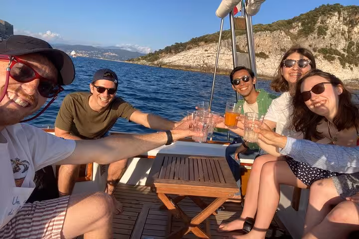 Friends toasting drinks on a boat tour around La Spezia, exploring Portovenere and nearby islands.