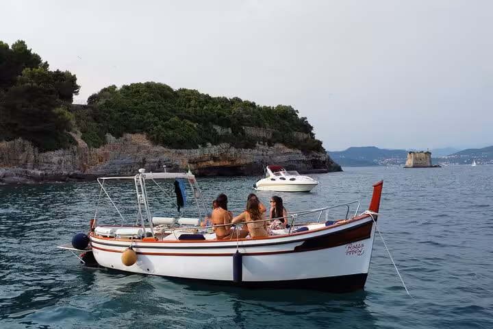 Tourists enjoy a scenic boat ride near the lush coastline of La Spezia, highlighting the Portovenere tour experience.