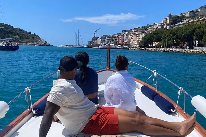 Passengers relax on a boat approaching the picturesque coastline of Lerici, with clear blue waters and charming architecture.
