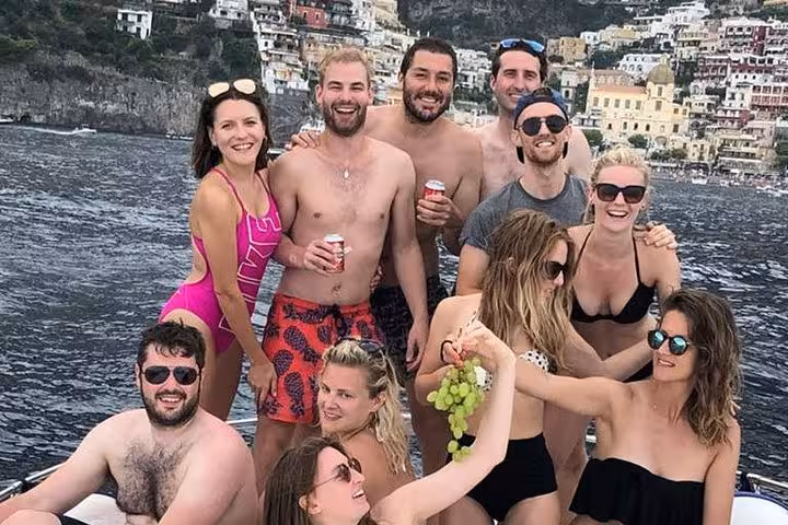 Group of friends enjoying a boat tour near Positano, capturing the vibrant coastal scenery.