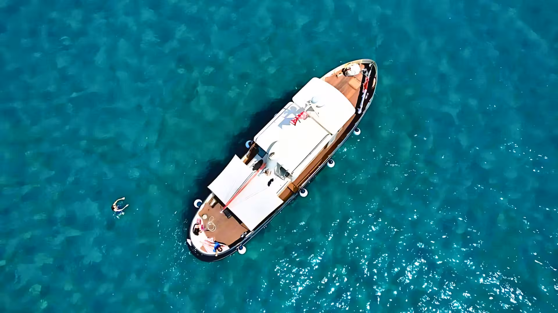 Aerial view of a boat sailing through turquoise waters near Golfo Aranci, perfect for Tavolara, Molara, and Figarolo tours.