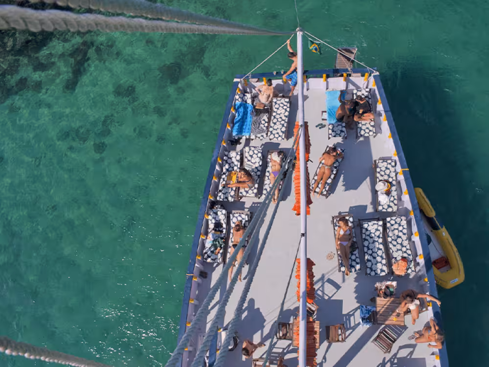 Aerial view of a boat deck with sunbathers enjoying the turquoise sea during a scenic boat trip.
