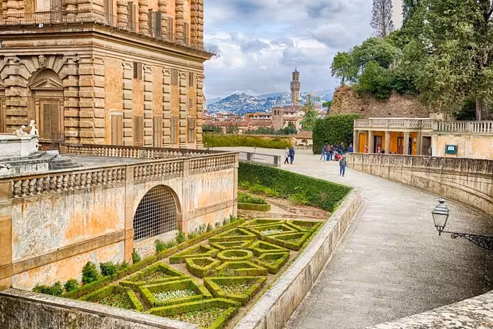 Lush greenery and historic architecture in the Boboli Gardens with a view of Florence's skyline in the distance.