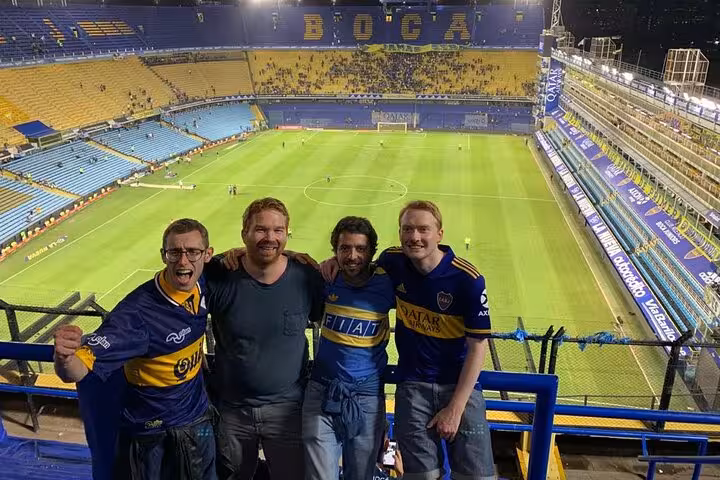 Fans in Boca Juniors jerseys inside La Bombonera stadium stands, guided matchday tour with transport in Buenos Aires