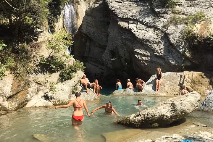 Visitors relaxing by serene waterfall pool, embodying Bogove's natural beauty and adventure.