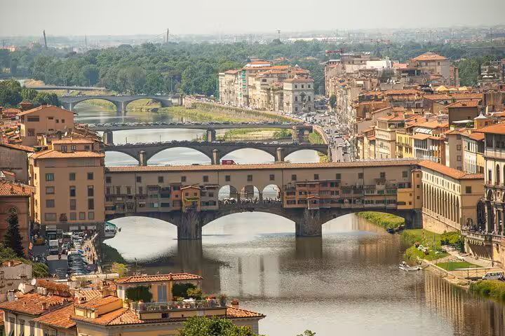 Aerial view of Florence's iconic Ponte Vecchio bridge over the Arno River, showcasing historic architecture and vibrant city life.