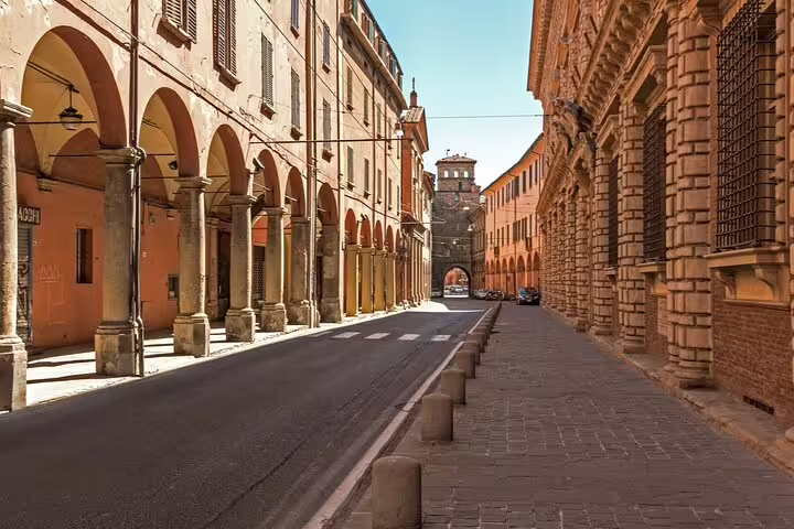Porticoed medieval street with terracotta buildings in Bologna's historic city center