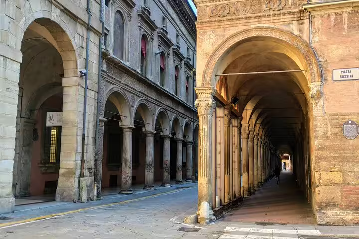 Historic porticoes and arched walkways along Piazza Rossini in Bologna's old town