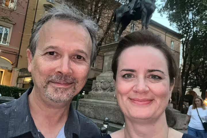 Couple smiling in front of a historic statue in Bologna's old town piazza