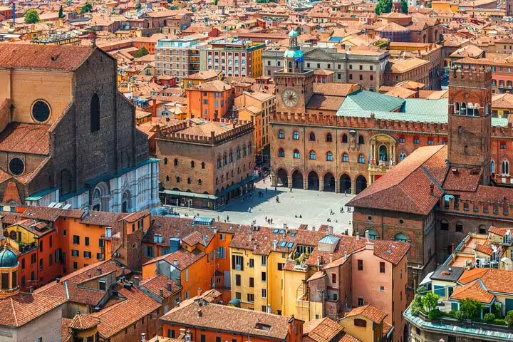 Aerial view of Bologna's Piazza Maggiore with terracotta rooftops, historic basilica and medieval clock tower