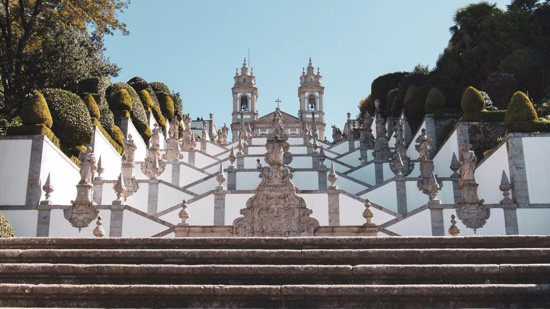 Majestic staircase leading to Bom Jesus do Monte sanctuary in Braga surrounded by lush greenery.